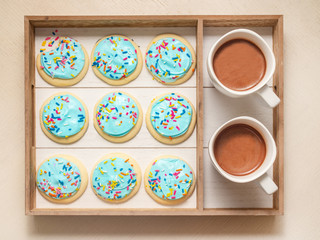 sugar cookies served on a wooden tray with cups of hot chocolate