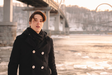 Portrait of teenage boy wearing coat and scarf while standing by river in winter