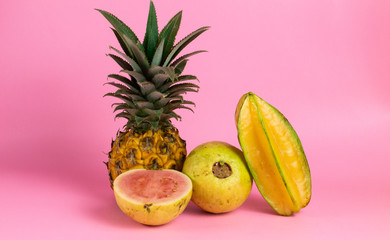 exotic tropical fruits, pineapple, starfruits isolated on a pink background