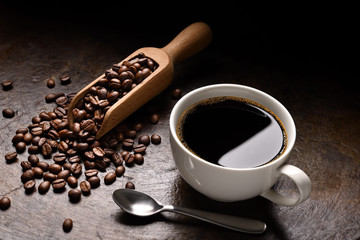 Cup of coffee and coffee beans in wooden spoon on rustic background