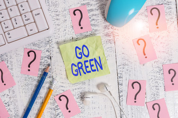 Word writing text Go Green. Business photo showcasing making more environmentally friendly decisions as reduce recycle Writing tools, computer stuff and scribbled paper on top of wooden table