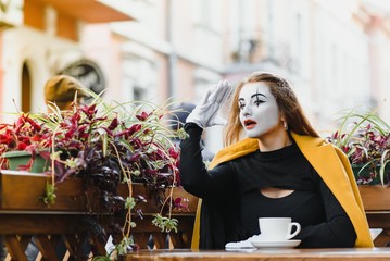 Mime comedian drinking coffee. girl mime drinks coffee in paris.