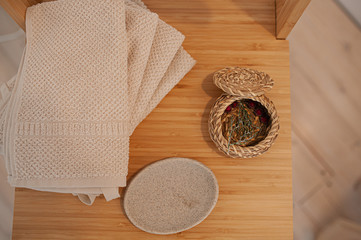 natural eco-friendly bath accessories, cotton towels, stone soap dish and wicker basket, on a wooden tabletop