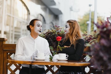mime guy and girl in cafe drinking coffee. Mime in front of Paris cafe acting like drinking tea or coffee.