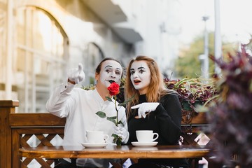 mime guy and girl in cafe drinking coffee. Mime in front of Paris cafe acting like drinking tea or...