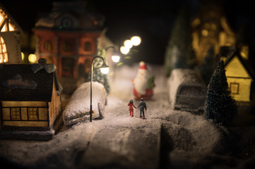 New Year miniature house in the snow at night with fir tree. Holiday concept. Selective focus