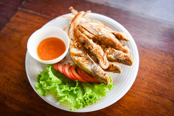 fried fish with vegetable salad tomato and sauce on white plate wooden table / freshwater fish Mekong River Other names Sheatfishes Siluriformes Siluridae