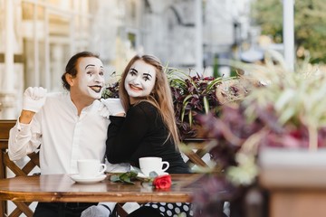 mime guy and girl in cafe drinking coffee. Mime in front of Paris cafe acting like drinking tea or coffee.