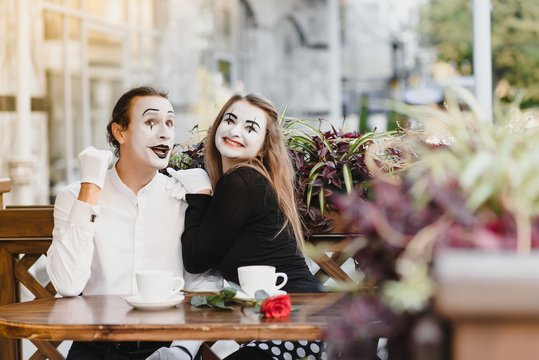 mime guy and girl in cafe drinking coffee. Mime in front of Paris cafe acting like drinking tea or coffee.