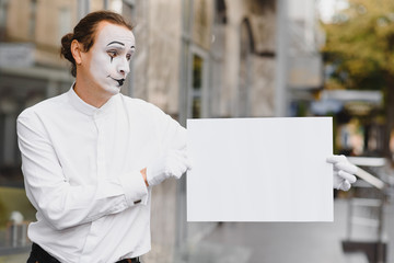 Your text here. Actor mime holding empty white letter. Colorful portrait with gray background. April fools day