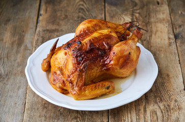 Whole baked chicken on old wooden background