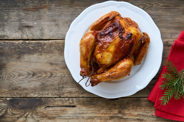 Whole baked chicken on old wooden background