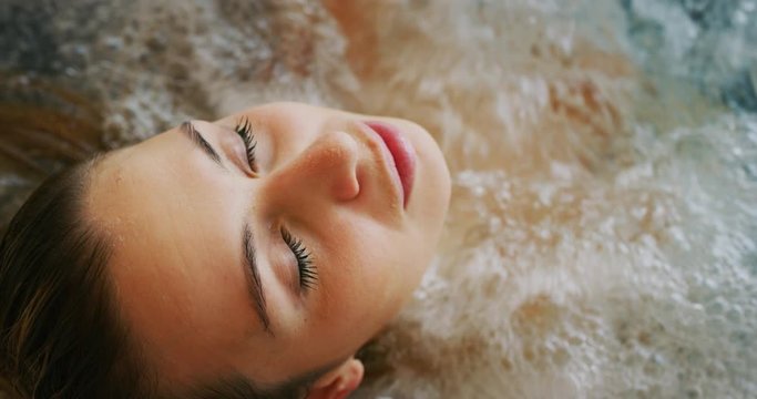 Close up of an young female is enjoying and having relax in a bath tube in a luxury wellness center.