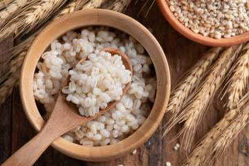 Cooked peeled barley grains in wooden bowl