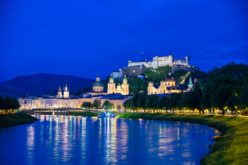 Fototapeta premium A view of Salzburg, Austria along the Salzach River at night.