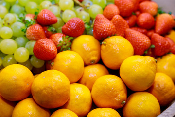 Fresh fruits. Tangerines and strawberries with grapes in soft focus.