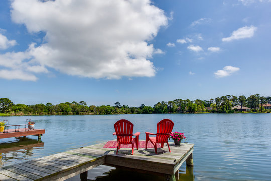 Two red chairs on a dock looking at the river
