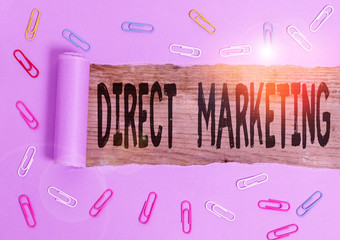 Conceptual hand writing showing Direct Marketing. Concept meaning business of selling products directly to the public Paper clip and torn cardboard on wood classic table backdrop