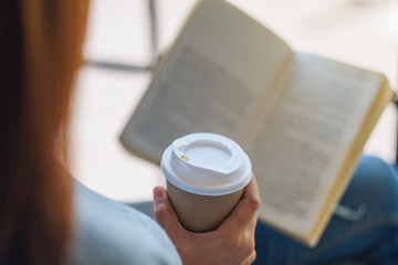 Closeup image of a woman reading book and drinking coffee in the morning