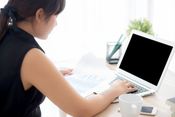 Beautiful asian woman working and typing with laptop computer at office, businesswoman looking graph diagram analysis statistic data of finance, girl using notebook, profit growth, business concept.
