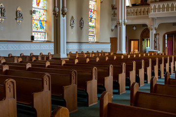 Inside of an ornate but empty Church cathedral showing symmetrical rows of pews 