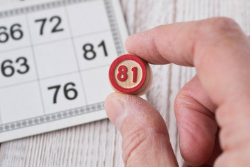 Human hand with a Lotto barrel. Play bingo or Lotto on a wooden table. Concept of Board games.