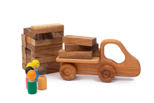 The wooden toy of the truck brought the building material in the form of logs to the construction site. Images of builders from children's toys. Construction and construction site concept