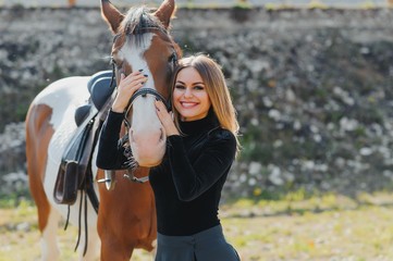 Obraz premium Young woman physiotherapist taking care a brown horse. Woman making a treatment in the shoulder, crest, forehead, muzzle and chin groove.