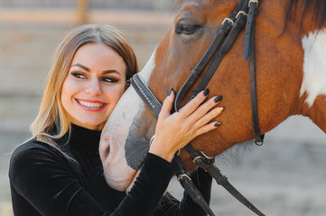 Portrait of young pretty cheerful woman with horse at summer