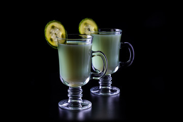 Kefir, greens and cucumber smoothie, a sour-milk drink. On a black background.