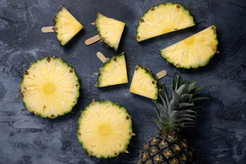 Slices of fresh Pineapple on simple grey background, from above. Top view. Copy space for designer.