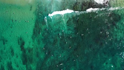 Top down aerial drone view from above surfers, surfing the waves below on a beautiful sunny day at destination.