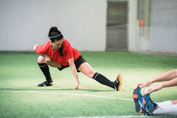 Active girl in sports uniform doing exercise for stretching legs before game