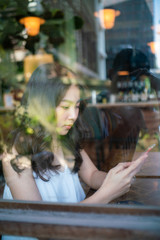 Obraz na płótnie Canvas Beautiful asian women use smartphone drinking coffe in cafe