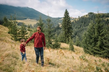Happy father and little son are walking in the mountains