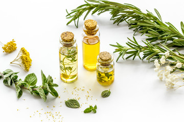 Aromatherapy. Essential oils in small bottles near fresh herbs on white background - obrazy, fototapety, plakaty