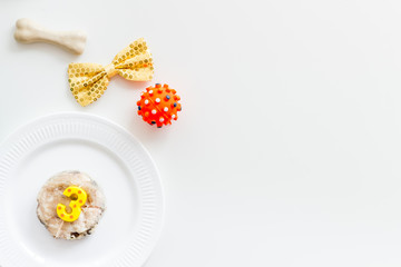 Birthday treat for puppy concept. Dog feed, candle in shape of number three, bone on white background top-down copy space