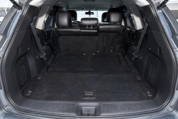 Luggage space in the body of the SUV car trunk with open rear door and leather interior after washing and dry cleaning with three rows of seats. Auto service industry. Travel concept.