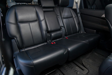 Fototapeta premium Clean after washing the rear passenger seats of matte black genuine leather inside the interior of an expensive SUV, preparation before selling the car.