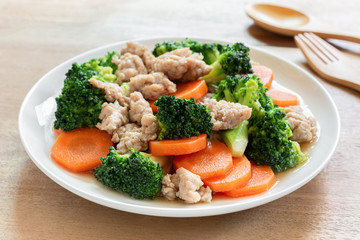 close up of stir fried broccoli with pork in a ceramic dish on wooden table. homemade style food concept.