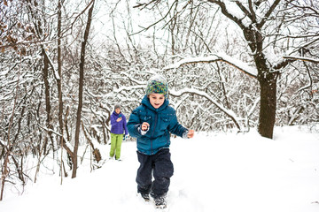 Fototapeta na wymiar The boy runs away from his mother on a snowy path.