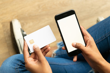 Woman of color holding a bank card and a cell phone