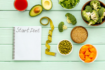 Diet program mockup. Start diet text in notebook near vegetables on green wooden background top view