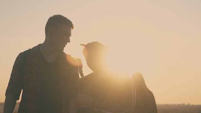 plump girl and happy guy walk with friends along meadow to camp in autumn evening at back sunlight slow motion