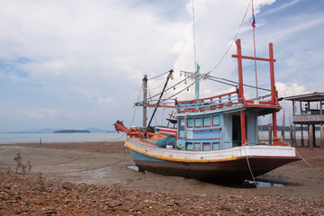 FIshing boat and wooden house at low tide beach, Koh Lanta island, Thailand.