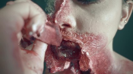 Make up artist working carefully with model, creating Zombie face for cinematic filming of horror movie