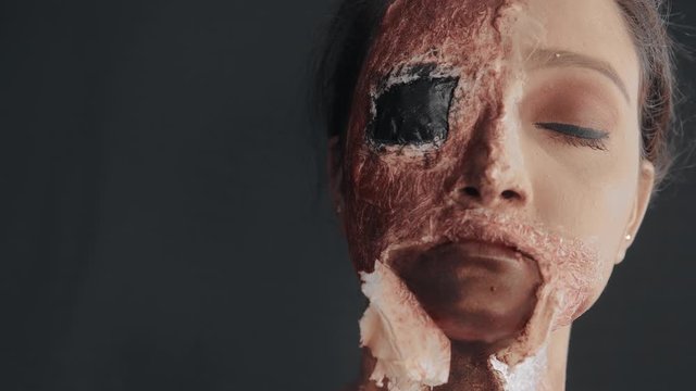 Close up of scary zombie mask on woman's face and make up artist perfecting it 