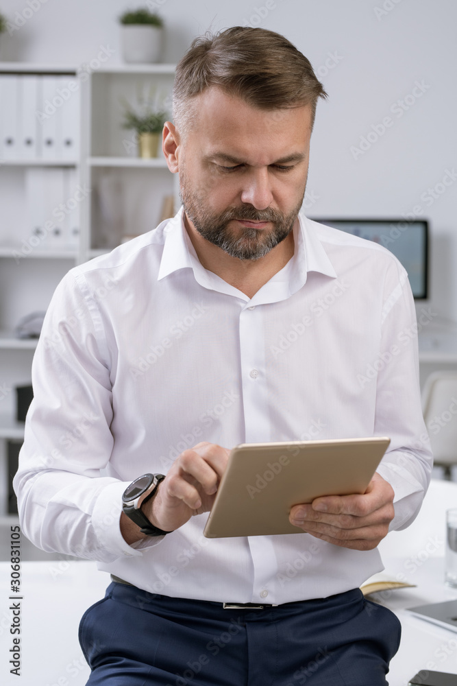 Poster elegant confident employer scrolling in touchpad while surfing for information