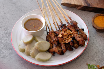 Goat satay with rice cake and peanut sauce, traditional food from Yogyakarta, Indonesia on the wooden table.