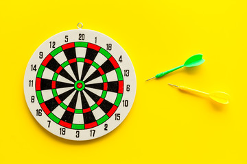 Goal achievement concept. Dartboard and arrows or dart on yellow background top view copy space